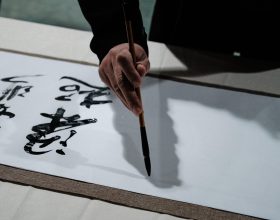 古代文人书房场景，文人手持毛笔在灯下书写，书案上摆放诗稿，营造白描写作的文人意境
